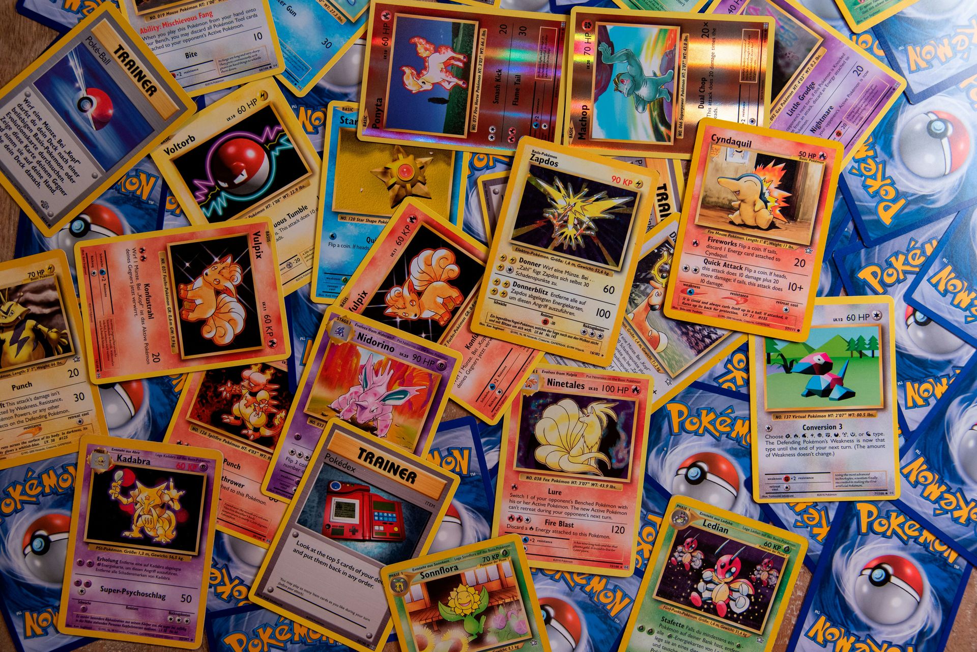 A collection of colorful Pokemon trading cards scattered across a flat surface